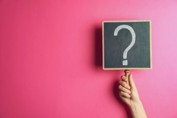 hand holding question mark sign on pink background depicting FAQs about Commercial Bulk Propane Storage