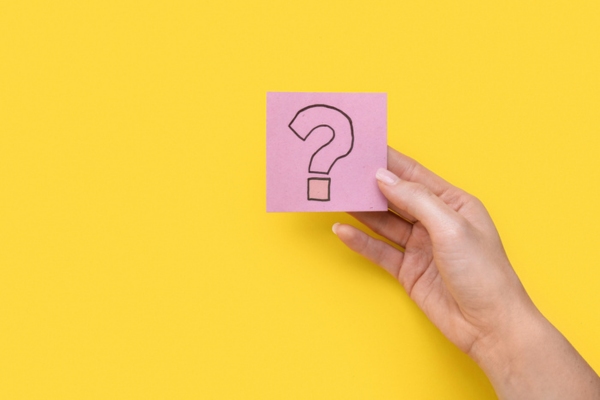 question mark on a sticky note held up by a woman's hand depicting Propane Delivery Company FAQs