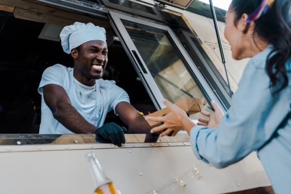 cheerful man serving order to a customer from a food truck