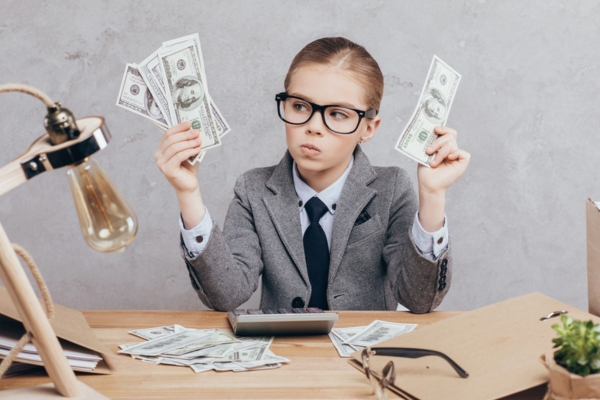 child wearing business suit while holding dollar bills