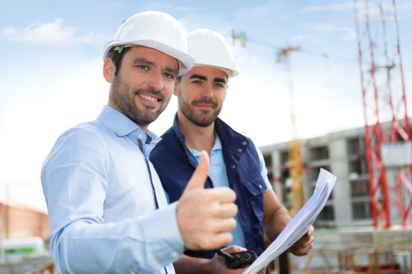 engineer doing a thumbs up with a worker while reviewing construction blueprint