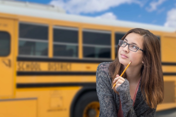 image of a female student thinking with school bus in the background depicting How a Professional Propane Supplier Supports School Bus Fleets