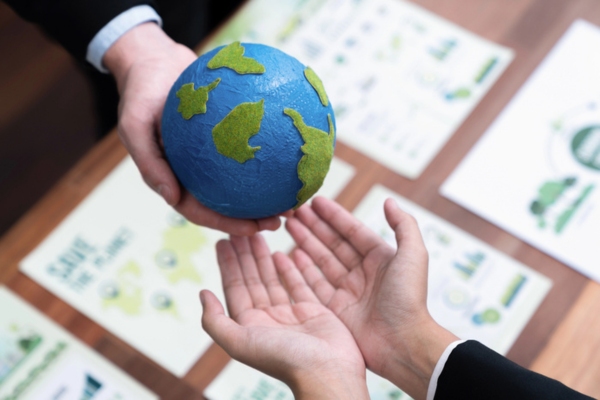two people holding a clay model of Earth together depicting Environmental Considerations