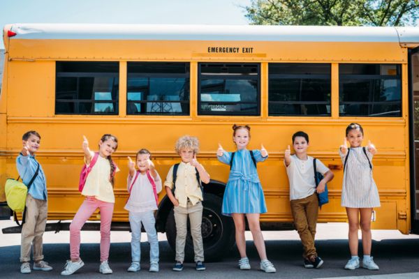 young students standing beside a school bus depicting Performance and Reliability of Propane School Buses